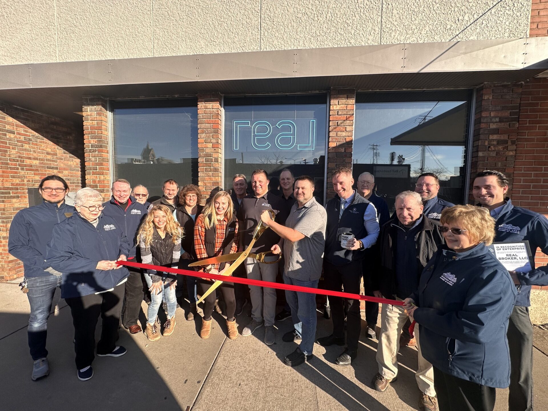 Group of Winona, Minnesota real estate agents cutting a ribbon with large scissors